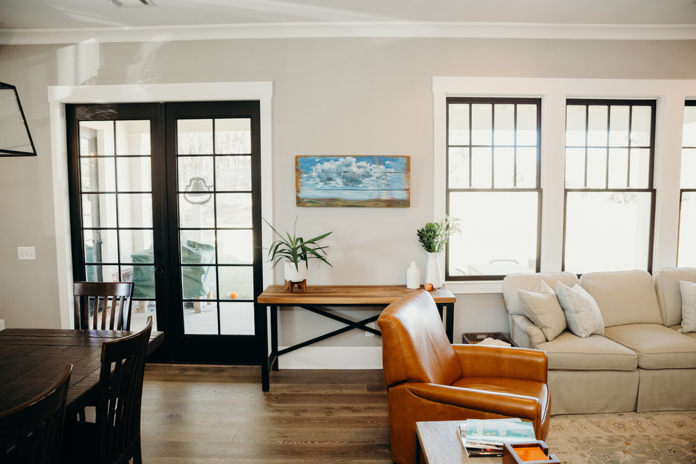 На фото: открытая гостиная комната среднего размера в стиле кантри с коричневыми стенами, паркетным полом среднего тона, стандартным камином, фасадом камина из кирпича, телевизором на стене и коричневым полом