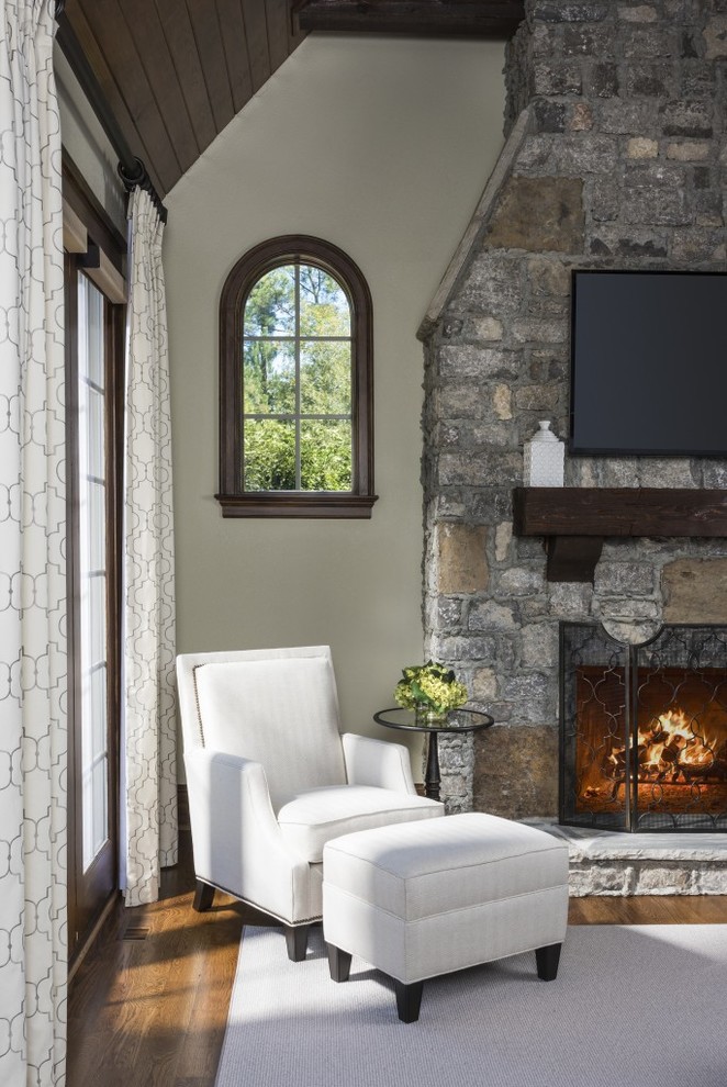Aménagement d'une grande salle de séjour classique ouverte avec un mur beige, une cheminée standard, un manteau de cheminée en pierre et un téléviseur fixé au mur.