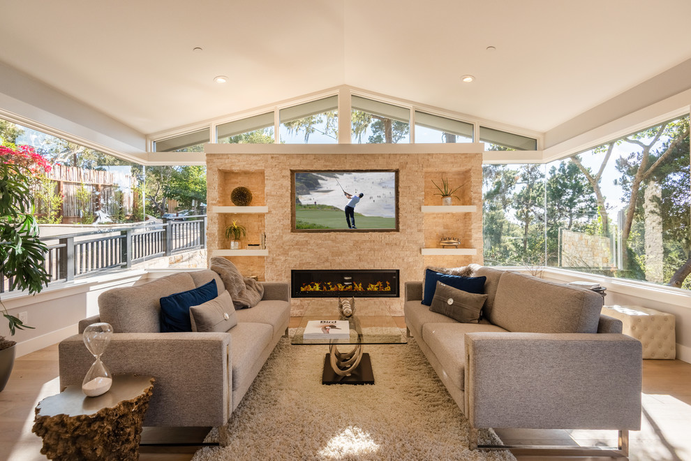 Ejemplo de sala de estar moderna de tamaño medio con suelo de madera en tonos medios, chimenea lineal, marco de chimenea de piedra y pared multimedia
