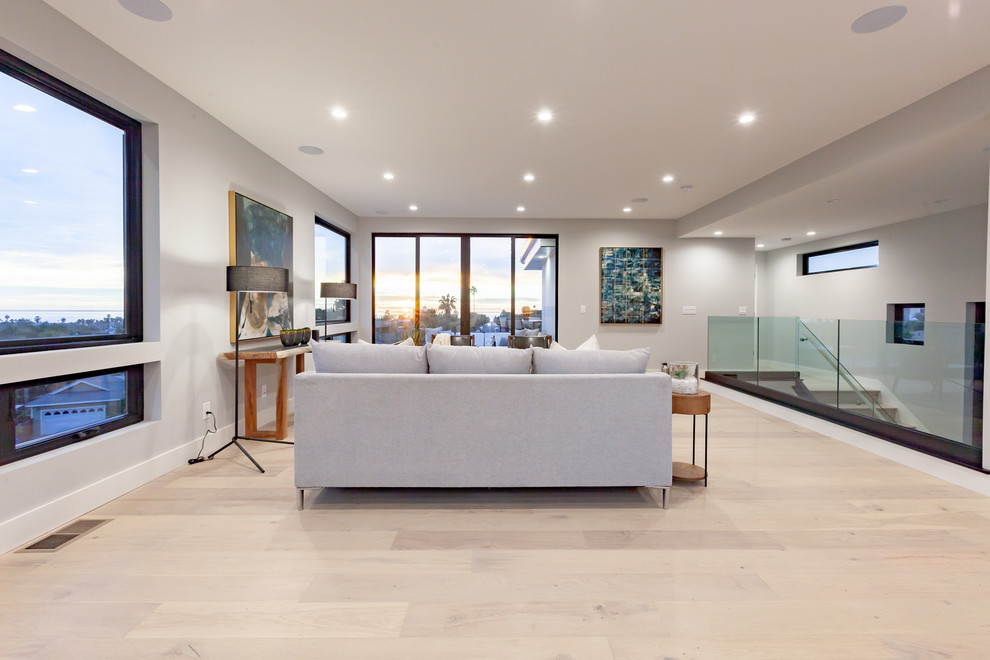 Ispirazione per un grande soggiorno design aperto con pareti grigie, parquet chiaro e pavimento beige