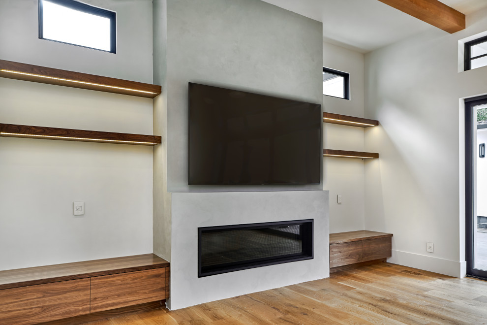 На фото: открытая гостиная комната среднего размера в стиле модернизм с белыми стенами, светлым паркетным полом, горизонтальным камином, фасадом камина из штукатурки, телевизором на стене и коричневым полом