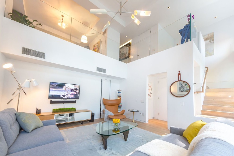На фото: изолированная гостиная комната среднего размера в стиле модернизм с белыми стенами, светлым паркетным полом и телевизором на стене без камина с