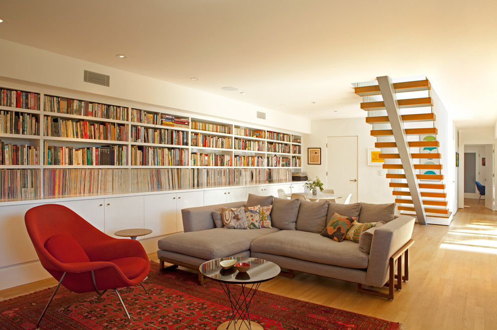 Exemple d'une grande salle de séjour rétro ouverte avec une bibliothèque ou un coin lecture, un mur blanc, parquet clair et un sol beige.