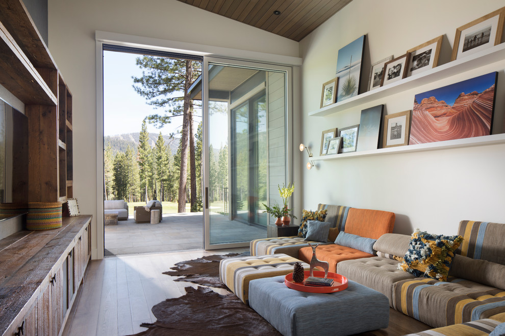 Modernes Wohnzimmer mit weißer Wandfarbe, braunem Holzboden, TV-Wand und braunem Boden in Sonstige