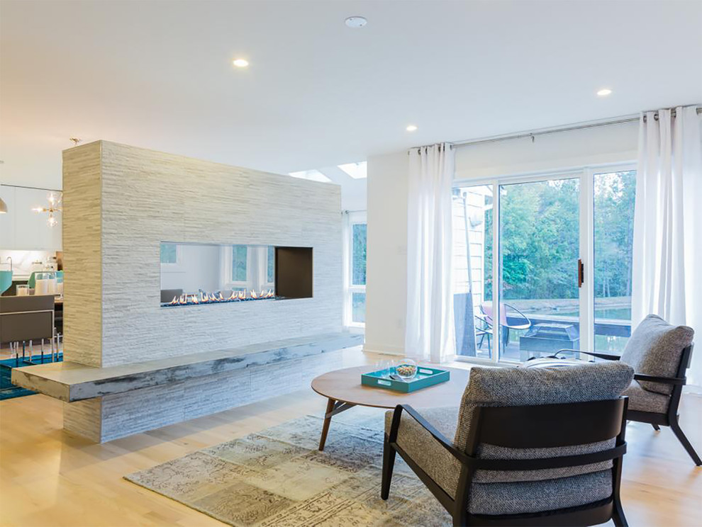 Inspiration for a large modern open plan games room in Boston with white walls, light hardwood flooring, a two-sided fireplace, a brick fireplace surround, a wall mounted tv and beige floors.