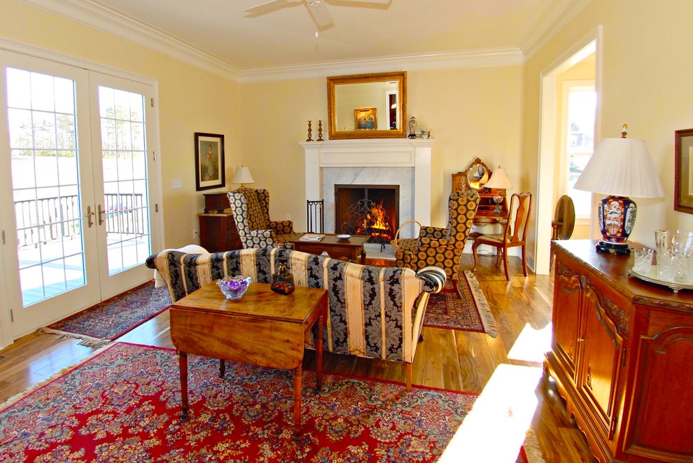На фото: открытая гостиная комната среднего размера в классическом стиле с желтыми стенами, паркетным полом среднего тона, стандартным камином, фасадом камина из камня и коричневым полом без телевизора