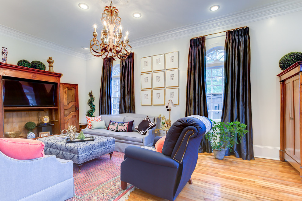 Diseño de sala de estar cerrada clásica grande sin chimenea con paredes blancas, suelo de madera en tonos medios, televisor colgado en la pared y suelo marrón