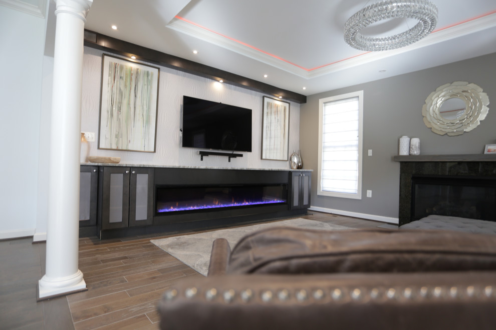 Cette image montre une salle de séjour traditionnelle de taille moyenne et ouverte avec un mur gris, un sol en bois brun, une cheminée standard, un manteau de cheminée en bois, un téléviseur encastré et un sol marron.