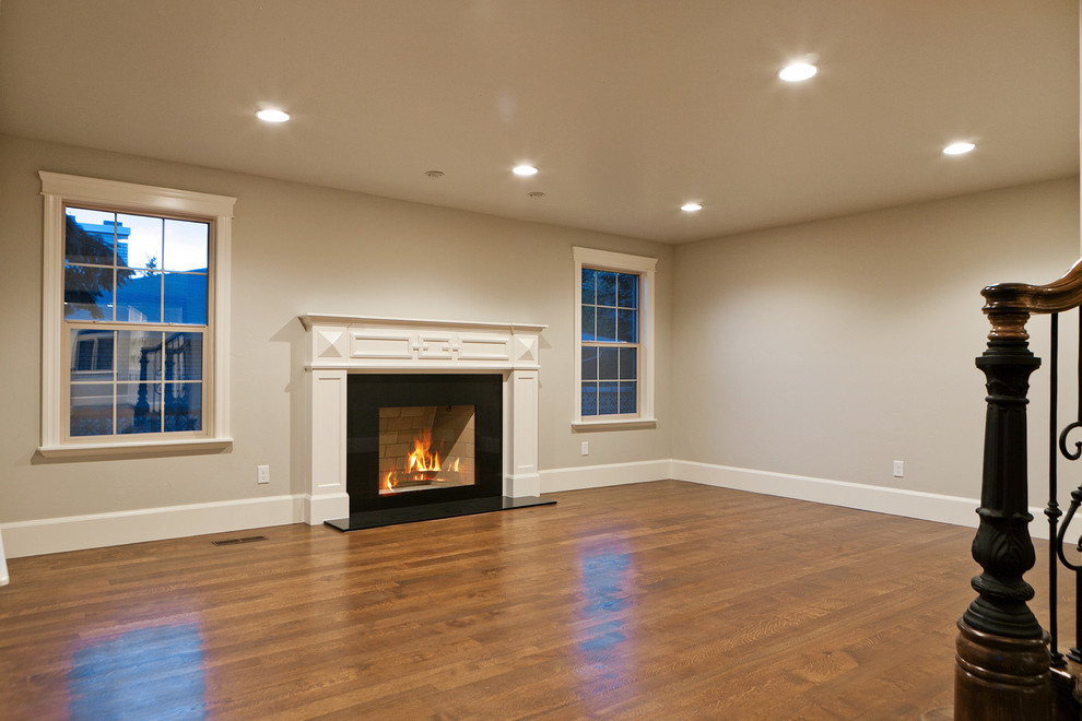 Imagen de sala de estar abierta clásica grande sin chimenea con paredes grises y suelo de madera en tonos medios