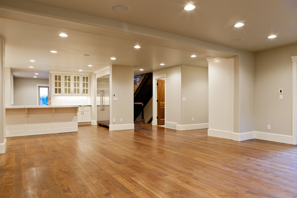 Ejemplo de sala de estar abierta clásica grande sin chimenea con paredes grises y suelo de madera en tonos medios