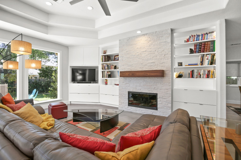 Photo of a medium sized contemporary open plan games room in Houston with a reading nook, grey walls, ceramic flooring, a standard fireplace, a stacked stone fireplace surround, a built-in media unit, grey floors and a drop ceiling.
