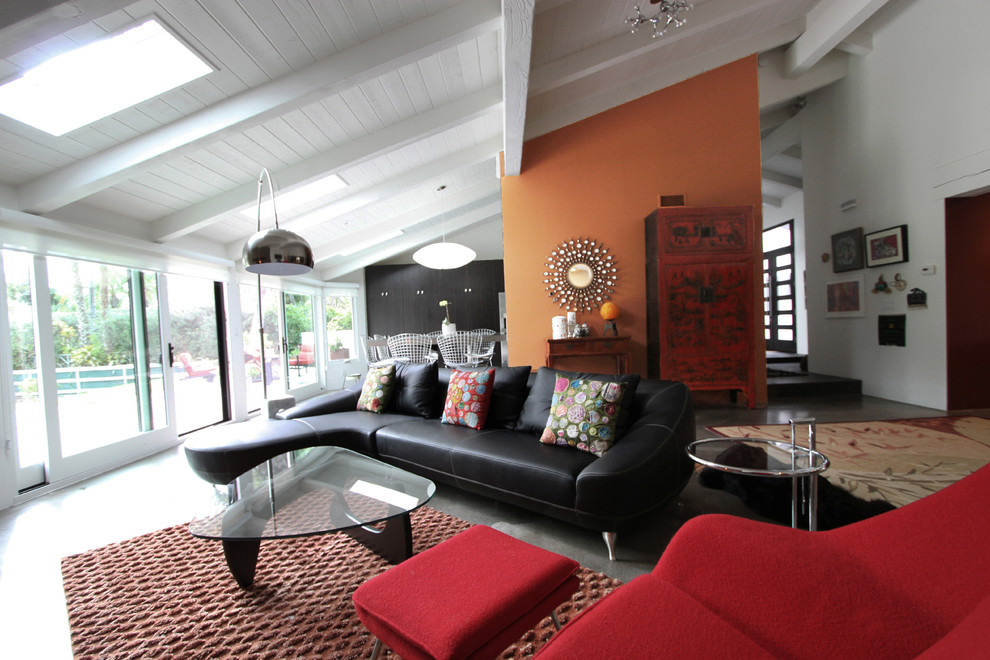 Réalisation d'une salle de séjour design ouverte avec un mur orange et sol en béton ciré.