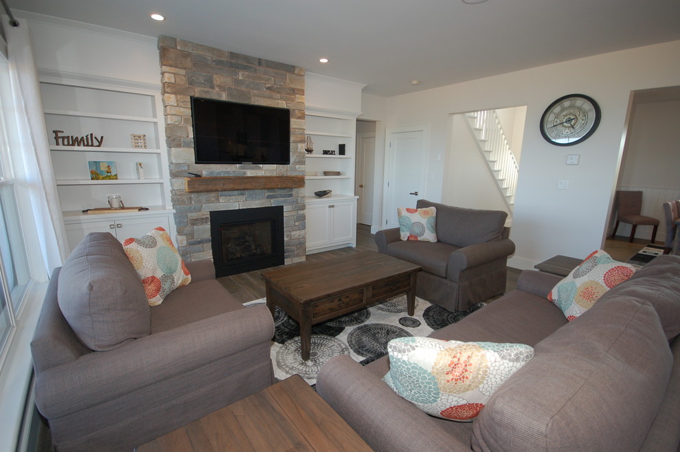 На фото: открытая гостиная комната среднего размера в классическом стиле с белыми стенами, темным паркетным полом, стандартным камином, фасадом камина из камня, телевизором на стене и коричневым полом