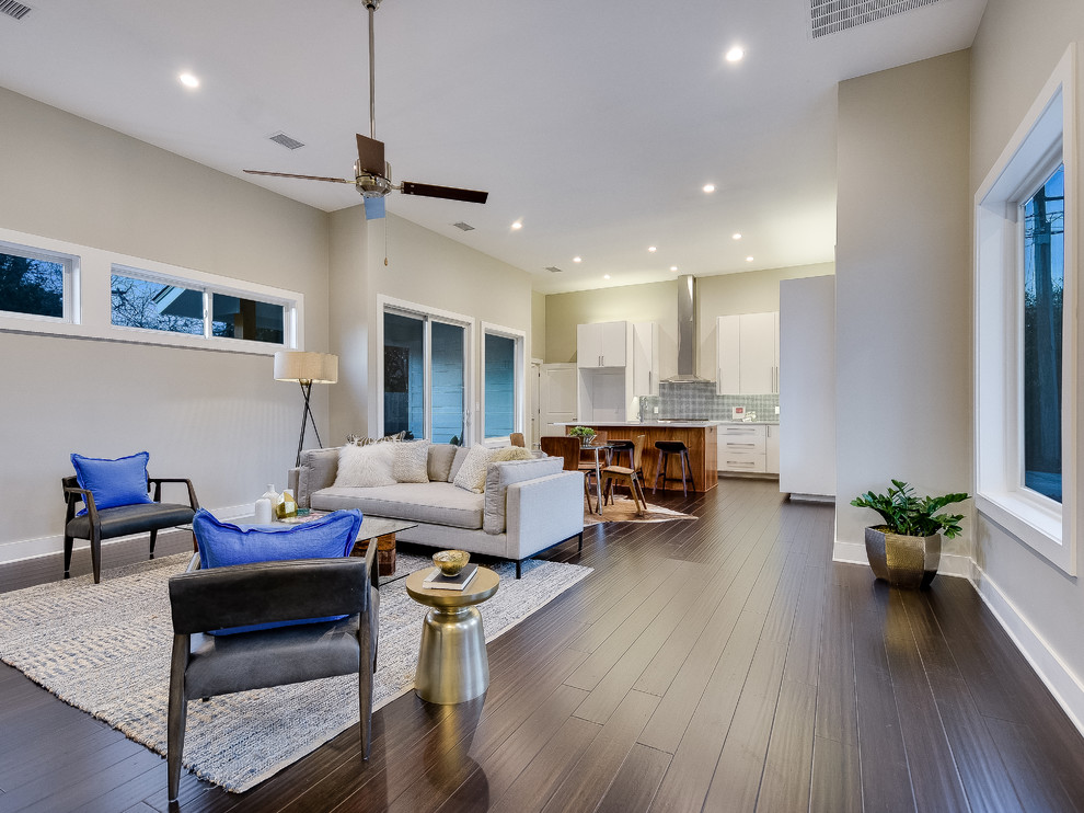Diseño de sala de estar abierta actual de tamaño medio con paredes grises, suelo de bambú, televisor colgado en la pared y suelo marrón