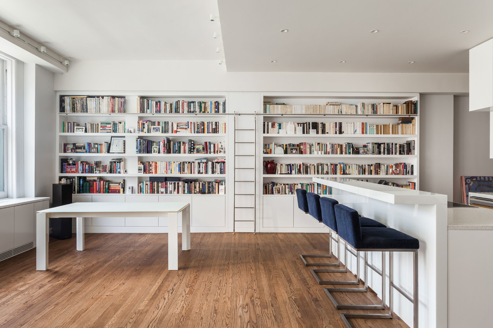 Immagine di un soggiorno minimalista aperto e di medie dimensioni con libreria e pareti bianche