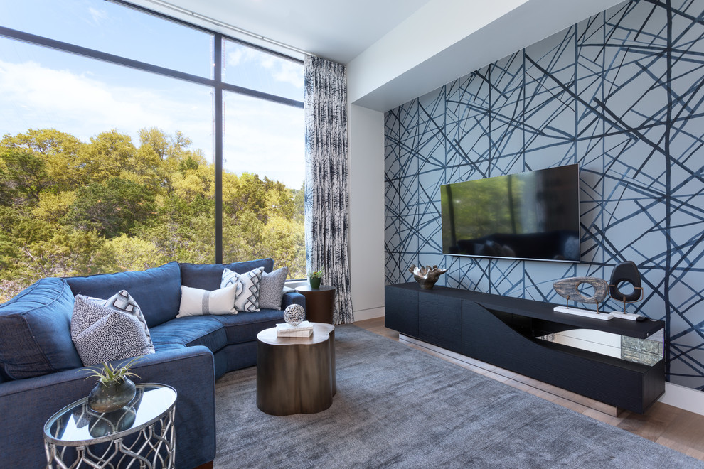 This is an example of a contemporary games room in Austin with grey walls, medium hardwood flooring, a wall mounted tv, brown floors and a feature wall.