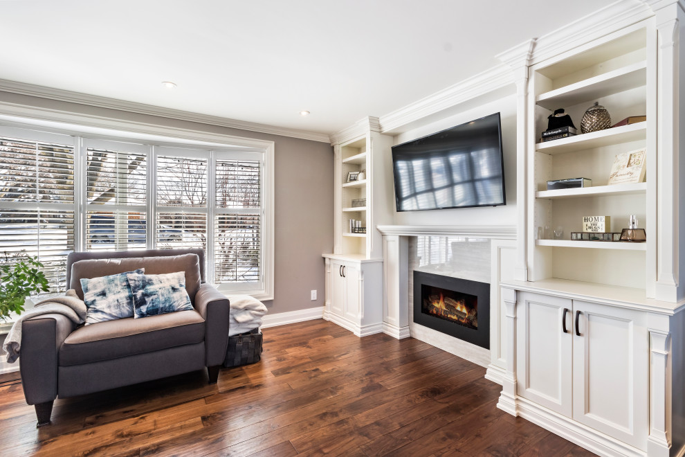 Inspiration for a large timeless open concept medium tone wood floor and brown floor family room remodel in Toronto with beige walls, a standard fireplace, a tile fireplace and a media wall