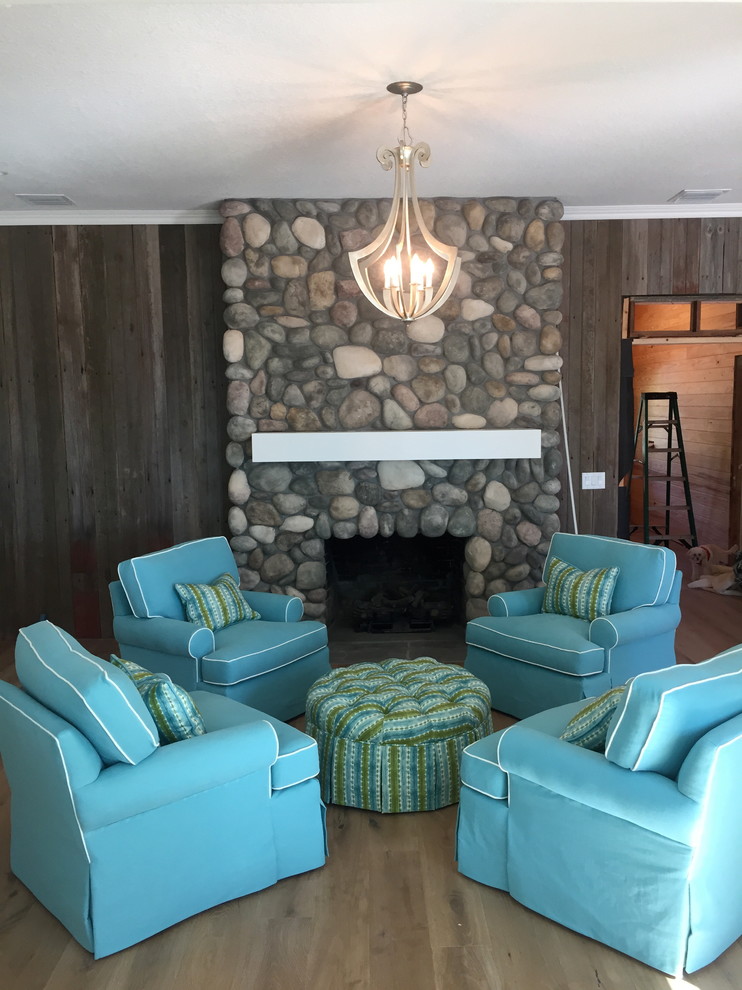 Maritimes Wohnzimmer mit hellem Holzboden und Kaminumrandung aus Stein in Orlando
