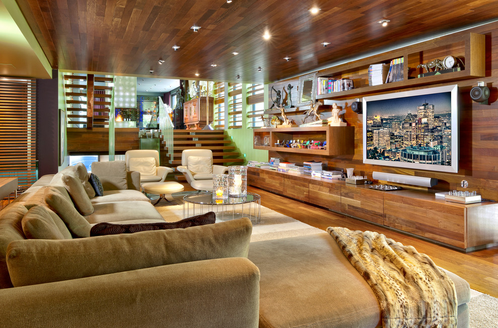 Ejemplo de sala de estar abierta contemporánea con paredes verdes, suelo de madera en tonos medios y televisor colgado en la pared