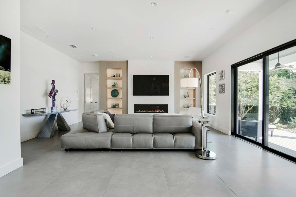 Идея дизайна: большая открытая гостиная комната в современном стиле с белыми стенами, полом из керамогранита, стандартным камином, фасадом камина из камня и телевизором на стене