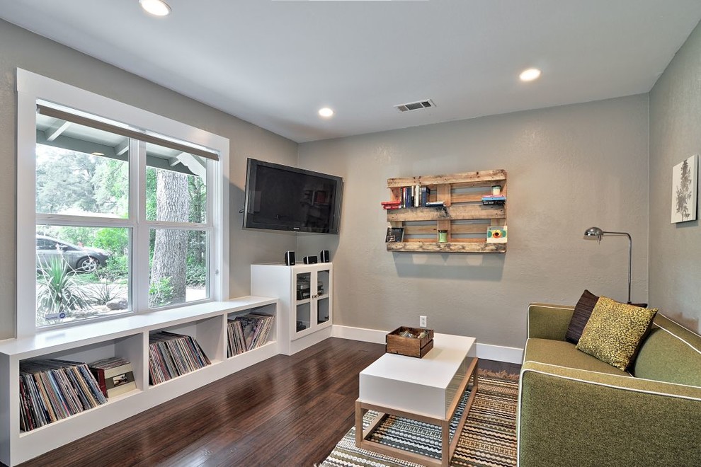 Стильный дизайн: изолированная гостиная комната в современном стиле с серыми стенами и телевизором на стене - последний тренд