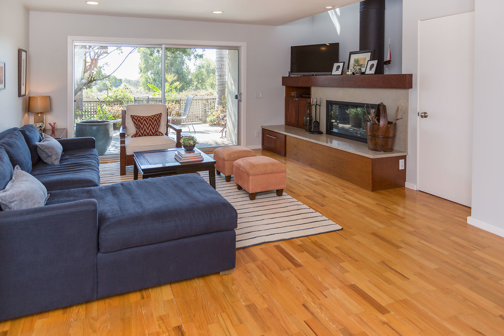 Kleines, Offenes Maritimes Wohnzimmer mit grüner Wandfarbe, hellem Holzboden, Kamin, Kaminumrandung aus Stein und Eck-TV in Los Angeles
