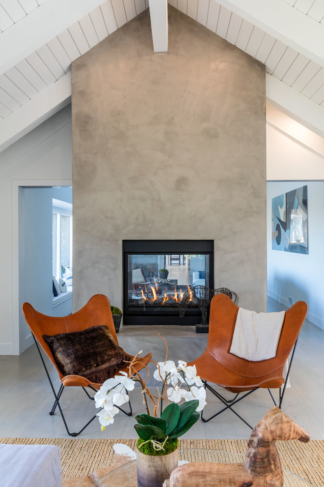 Ejemplo de sala de estar tradicional renovada con paredes blancas, suelo de madera clara, marco de chimenea de hormigón y chimenea de doble cara