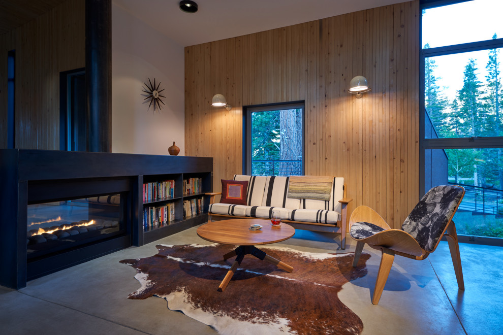Modelo de sala de estar abierta contemporánea con paredes marrones, suelo de cemento, chimenea lineal, suelo gris y madera
