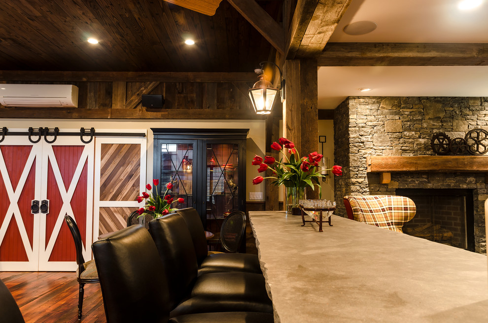 Aménagement d'une grande salle de séjour campagne ouverte avec un mur beige, un sol en bois brun, une cheminée standard, un manteau de cheminée en pierre et un téléviseur fixé au mur.