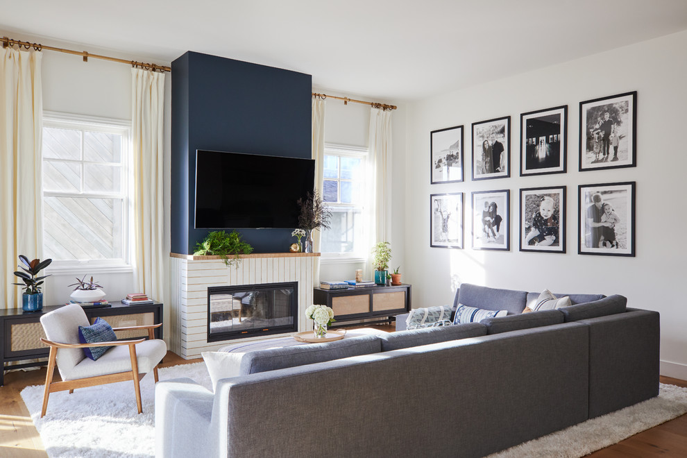 Foto de sala de estar abierta marinera con paredes blancas, suelo de madera en tonos medios, chimenea lineal, televisor colgado en la pared y alfombra