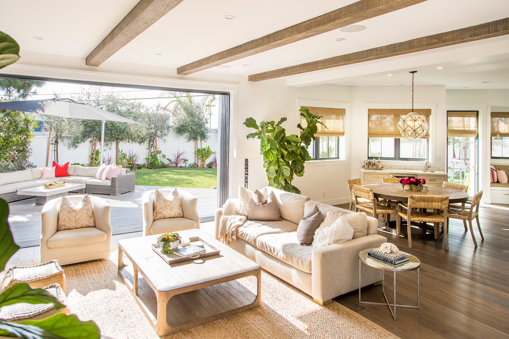 Diseño de sala de estar abierta costera con paredes blancas, suelo de madera en tonos medios, televisor colgado en la pared y suelo marrón