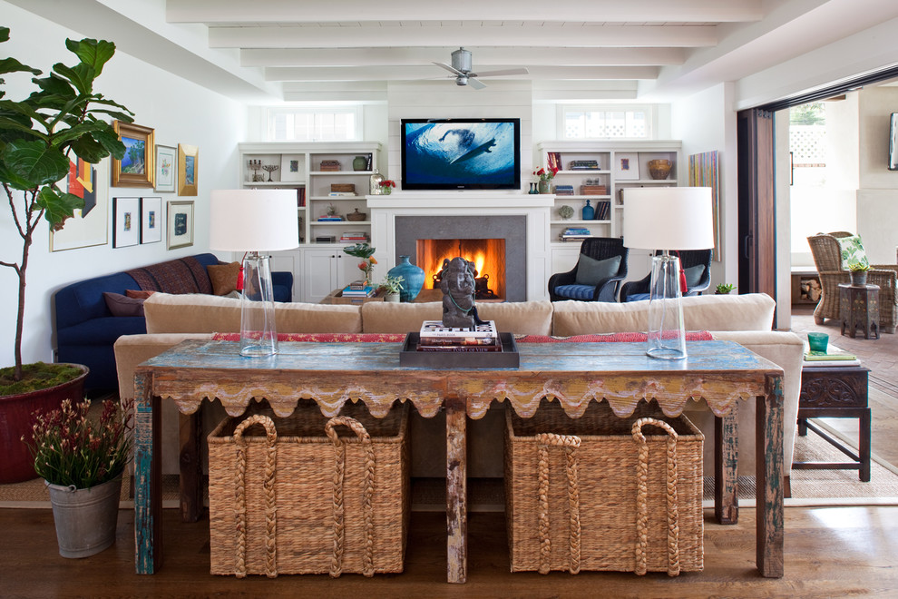 Example of a beach style medium tone wood floor family room design in Los Angeles with white walls, a standard fireplace, a stone fireplace and a wall-mounted tv