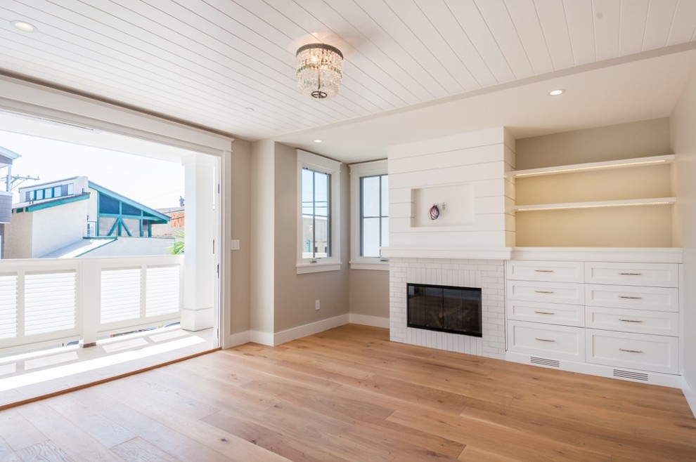 Imagen de sala de estar abierta campestre grande con paredes beige, suelo de madera en tonos medios, todas las chimeneas, marco de chimenea de ladrillo y pared multimedia