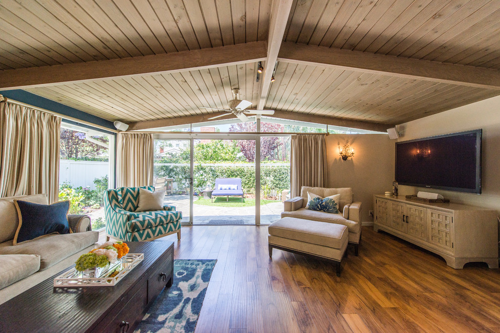 Diseño de sala de estar abierta costera de tamaño medio sin chimenea con paredes azules, suelo de madera en tonos medios y televisor colgado en la pared