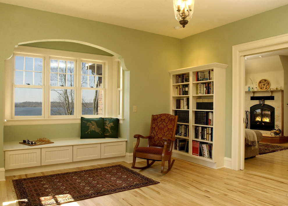 Mittelgroße, Offene Klassische Bibliothek mit grüner Wandfarbe, hellem Holzboden, Kamin, Kaminumrandung aus Stein und beigem Boden in Sonstige