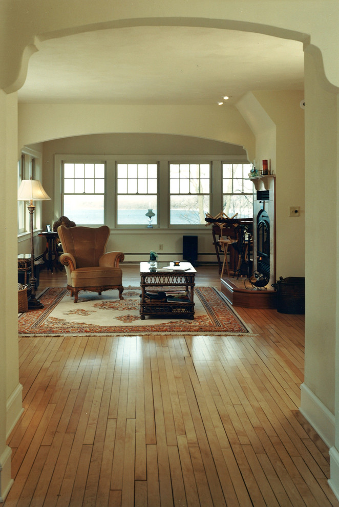 Foto de sala de estar con biblioteca abierta tradicional de tamaño medio con suelo de madera clara, todas las chimeneas, marco de chimenea de piedra, paredes verdes y suelo beige