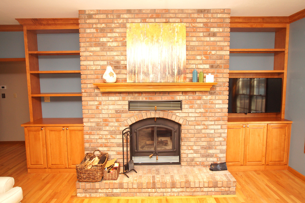 Medium sized traditional open plan games room in St Louis with blue walls, light hardwood flooring, a standard fireplace, a brick fireplace surround, a built-in media unit and brown floors.