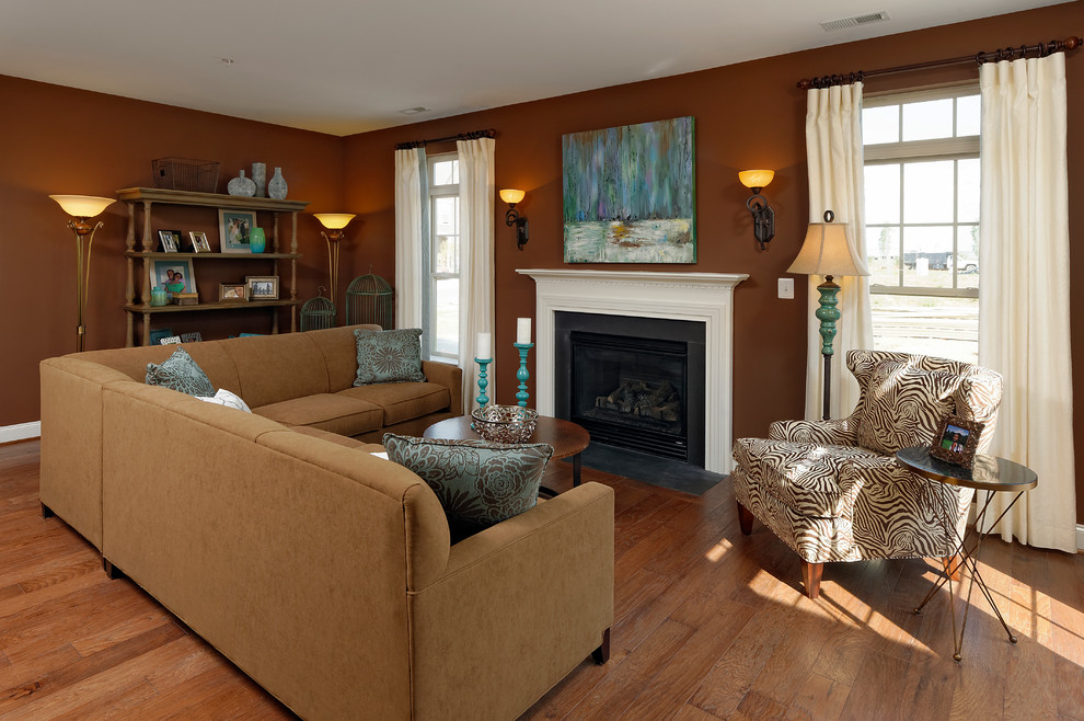 Réalisation d'une salle de séjour tradition de taille moyenne avec un mur marron, un sol en bois brun, une cheminée standard et un manteau de cheminée en pierre.