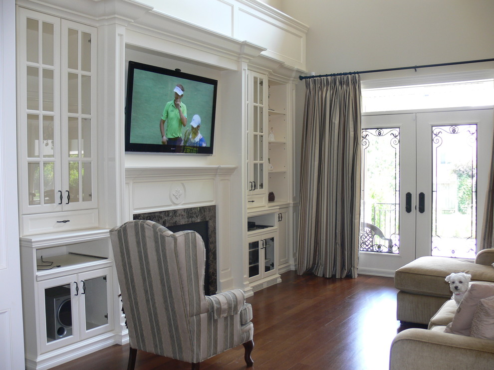 This is an example of a medium sized traditional open plan games room in Toronto with beige walls, medium hardwood flooring, a standard fireplace, a stone fireplace surround and a wall mounted tv.