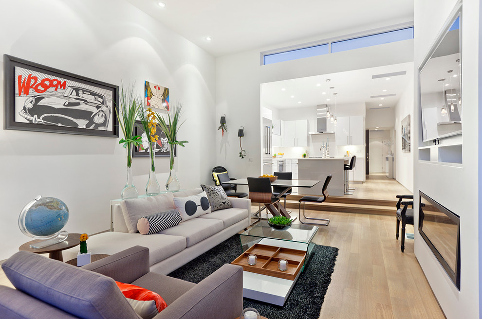 На фото: открытая гостиная комната в современном стиле с белыми стенами, светлым паркетным полом, горизонтальным камином, телевизором на стене и ковром на полу с