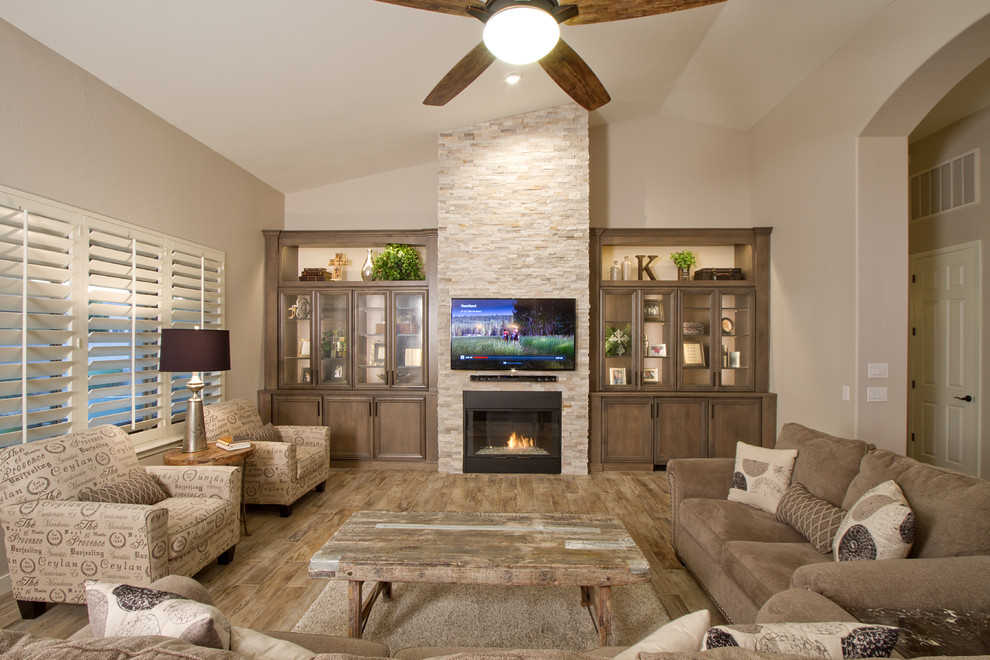 Large transitional open concept medium tone wood floor and brown floor family room photo in Phoenix with beige walls, a standard fireplace, a stone fireplace and a wall-mounted tv