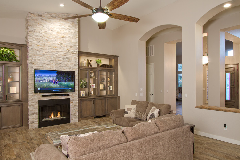 Offenes Klassisches Wohnzimmer mit grauer Wandfarbe, Porzellan-Bodenfliesen, Kamin, Kaminumrandung aus Stein und TV-Wand in Phoenix