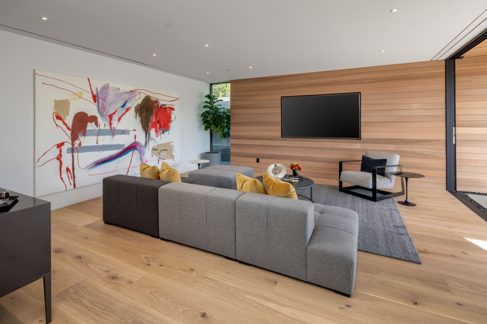 Offenes Modernes Wohnzimmer mit weißer Wandfarbe, hellem Holzboden, TV-Wand, beigem Boden und Holzwänden in Orange County