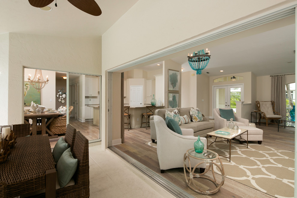 Modelo de sala de estar abierta costera con paredes beige, suelo de madera en tonos medios y pared multimedia