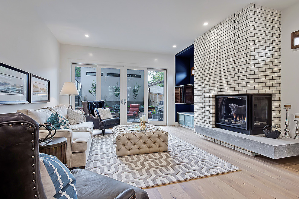 Mittelgroßes, Offenes Modernes Wohnzimmer mit weißer Wandfarbe, hellem Holzboden, Eckkamin und Kaminumrandung aus Backstein in Calgary
