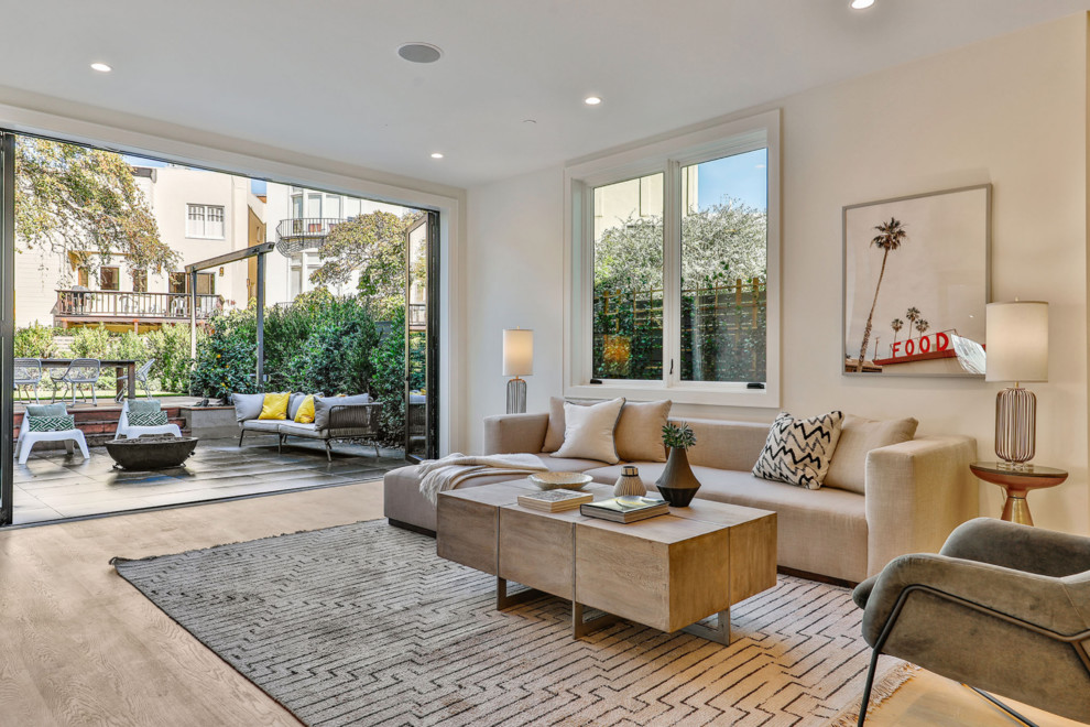 Example of a large trendy open concept light wood floor and beige floor family room design in San Francisco with white walls