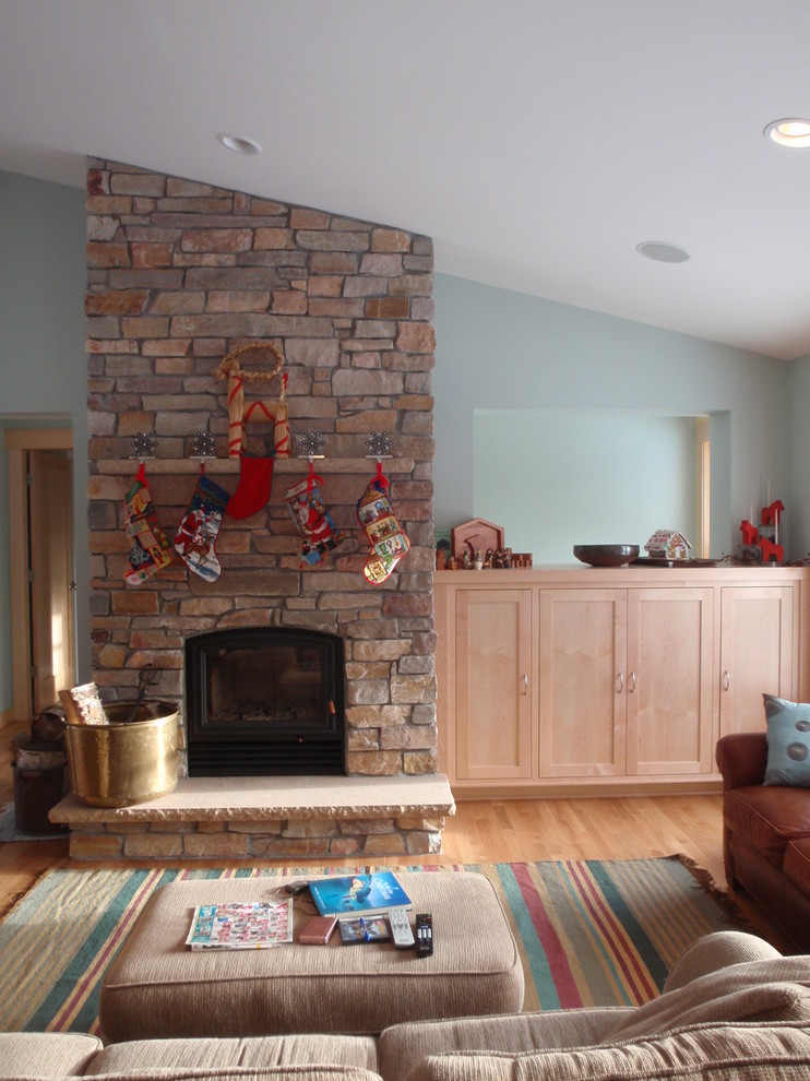 Family room - mid-sized eclectic open concept medium tone wood floor family room idea in Minneapolis with blue walls, a standard fireplace, a stone fireplace and a concealed tv