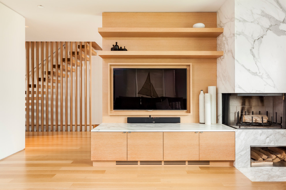 Mittelgroßes, Offenes Nordisches Wohnzimmer mit weißer Wandfarbe, hellem Holzboden, Eckkamin, Kaminumrandung aus Stein und Multimediawand in Toronto
