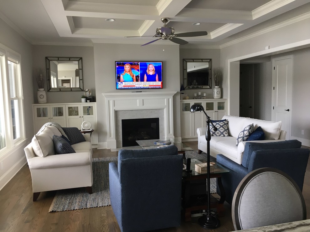 Großes, Offenes Klassisches Wohnzimmer mit grauer Wandfarbe, braunem Holzboden, Kamin, TV-Wand und braunem Boden in Charlotte