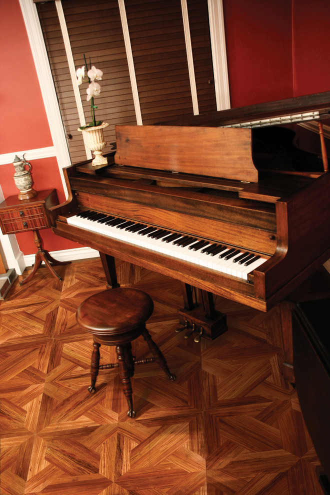 Aménagement d'une salle de séjour classique avec une salle de musique, un mur rouge et un sol en bois brun.